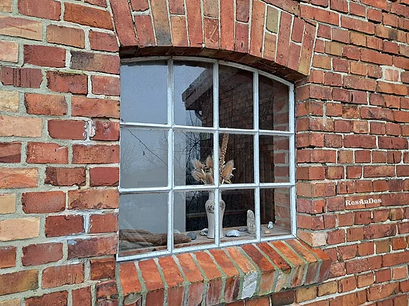 Aus historischen Ziegeln gemauerte Wand mit historischem Industriefenster aus Gusseisen